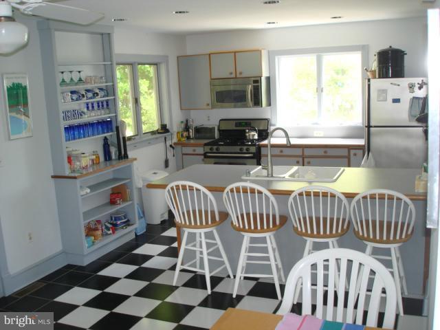 49588 Will's Road Dameron, MD 20628 - Photo 22 of 30 a kitchen with stainless steel appliances kitchen island granite countertop a refrigerator a sink a stove a dining table and chairs with wooden floor