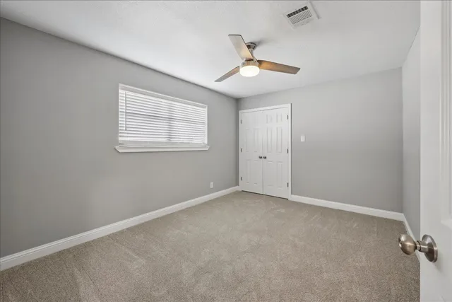 an empty room with a window and ceiling fan