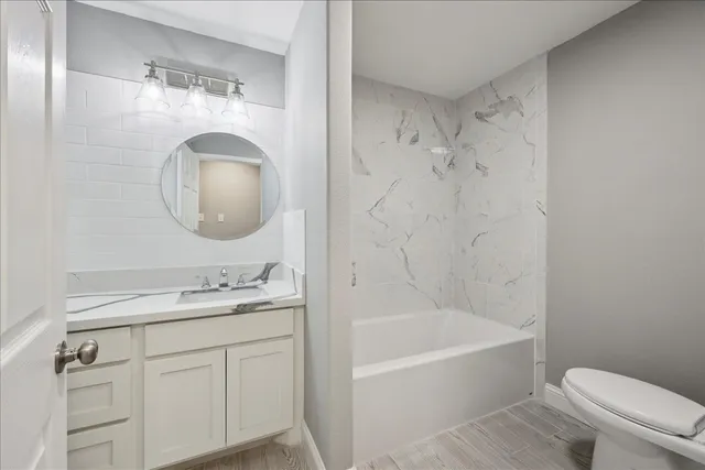 a bathroom with a granite countertop sink a toilet tub and a mirror