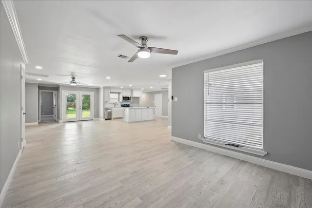 a view of an empty room with a window and wooden floor