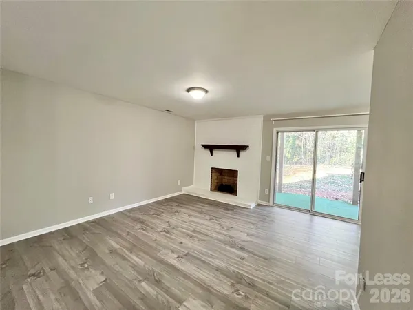 a view of empty room with wooden floor and fireplace