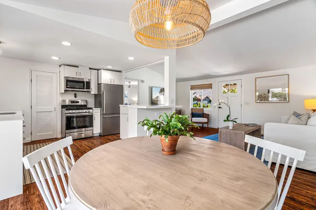 a kitchen with stainless steel appliances kitchen island granite countertop a refrigerator a stove a sink dishwasher and a dining table with wooden floor