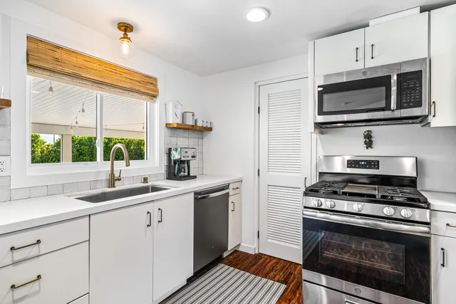 a kitchen with cabinets stainless steel appliances a sink and a window