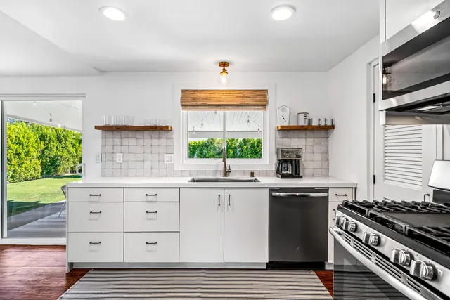 a kitchen with granite countertop a sink a stove a window cabinets and a dining table