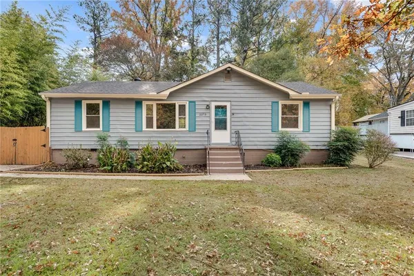 a front view of house with yard and trees all around