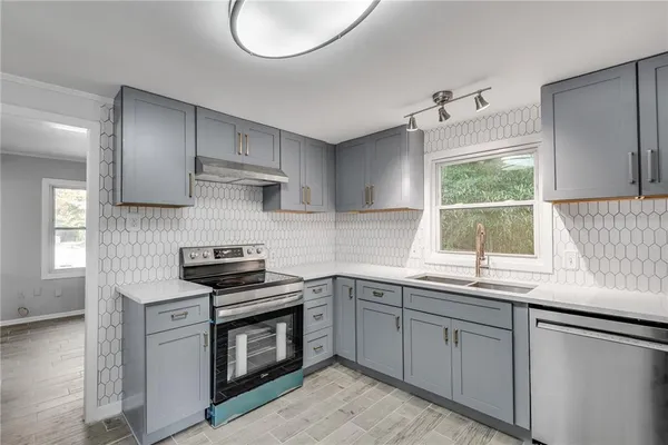 a kitchen with stainless steel appliances granite countertop a sink a stove and a window