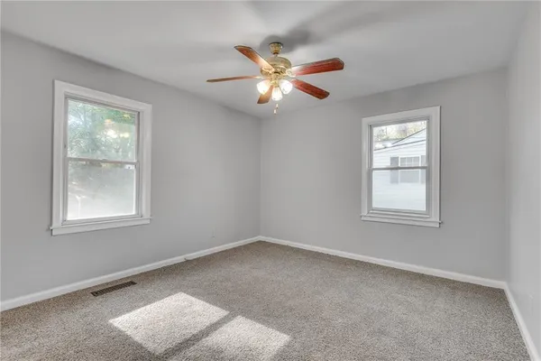 a view of an empty room with window and chandelier fan