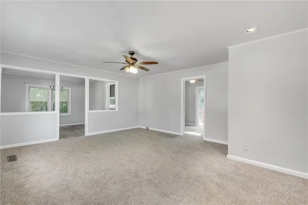 a view of an empty room with chandelier fan