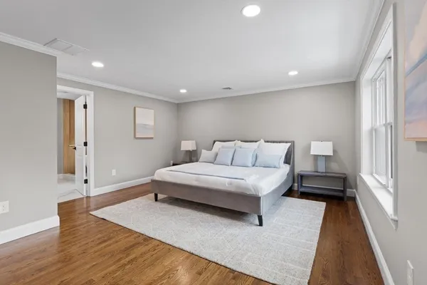a living room with a bed and a walk in closet with wooden floor