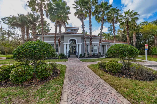 a front view of a house with a garden and palm trees