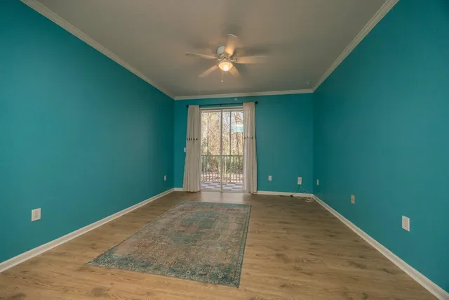 a view of a room with a large window and ceiling fan