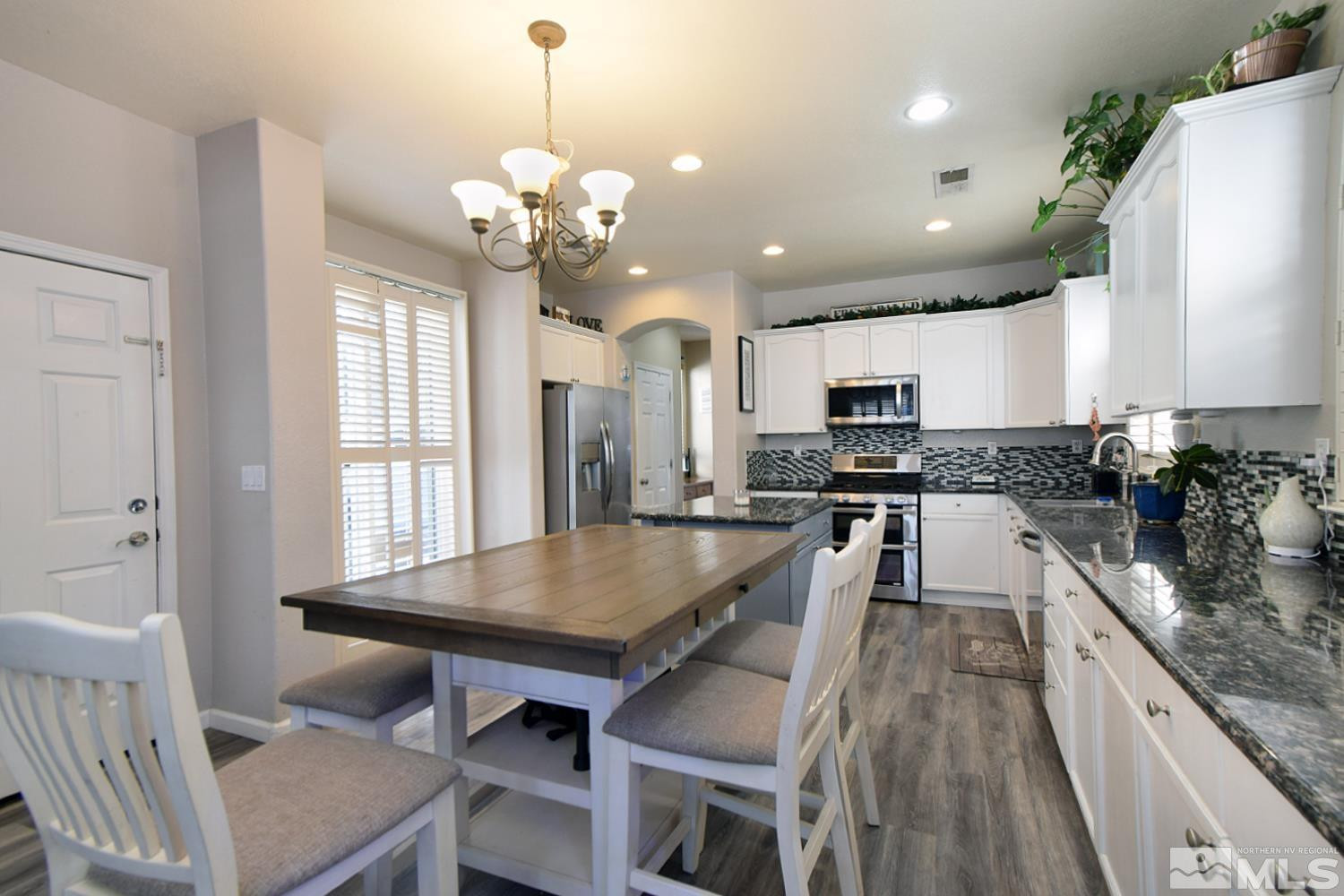 9335 Hummer Court Reno, NV 89521 - Photo 5 of 24 a kitchen with stainless steel appliances granite countertop a stove refrigerator a sink dishwasher a dining table and chairs with wooden floor