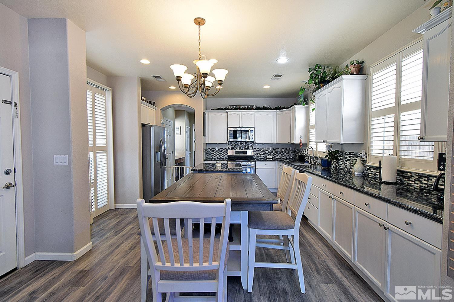 9335 Hummer Court Reno, NV 89521 - Photo 6 of 24 a kitchen with stainless steel appliances kitchen island granite countertop a dining table chairs and granite counter tops