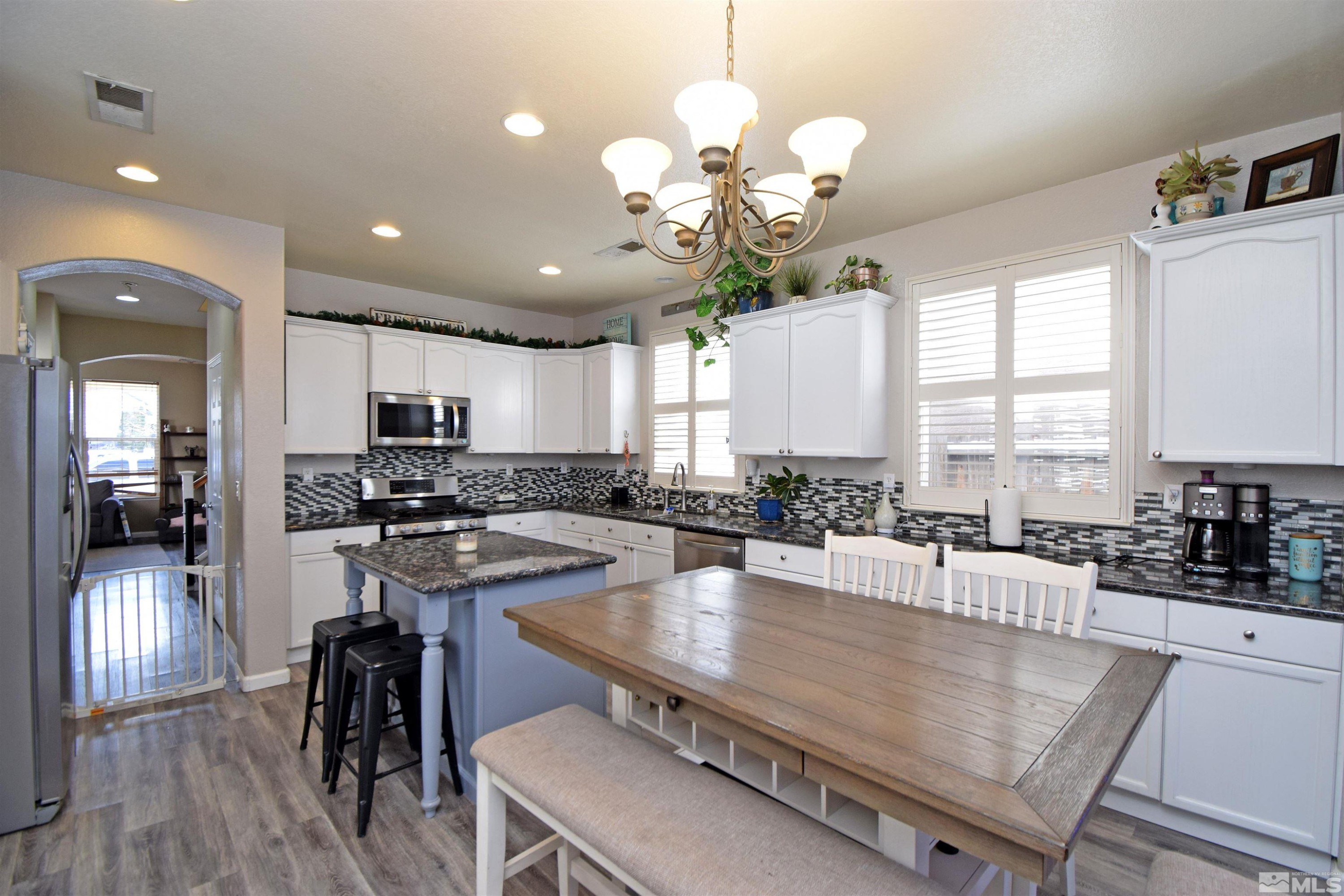 9335 Hummer Court Reno, NV 89521 - Photo 7 of 24 a kitchen with stainless steel appliances granite countertop a stove a refrigerator a sink a dining table and chairs