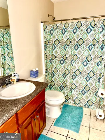 a bathroom with a sink a toilet a mirror and shower curtain
