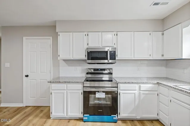 a kitchen with stainless steel appliances granite countertop a stove and white cabinets