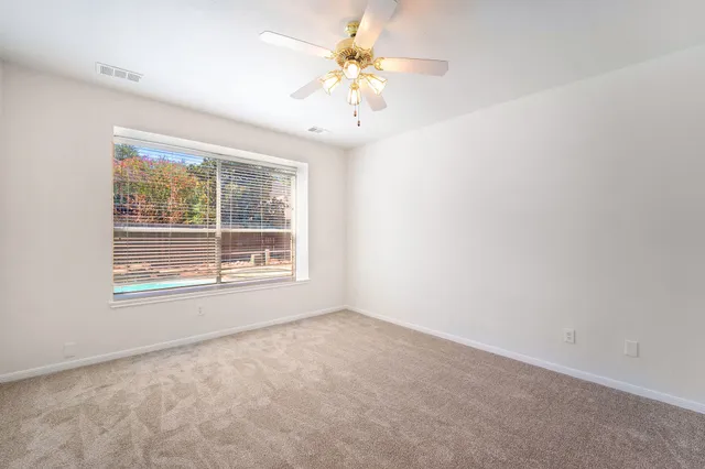 an empty room with a window and a chandelier fan