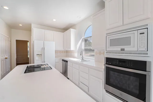 a kitchen with granite countertop cabinets stainless steel appliances and wooden floor