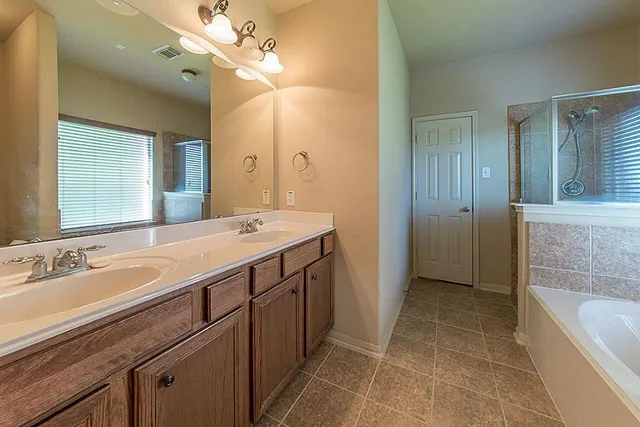 a spacious bathroom with a tub sink and mirror