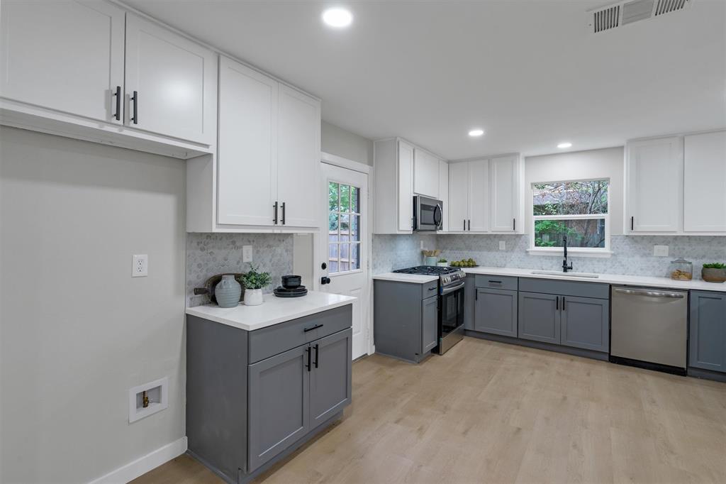 4815 Kelman Street Dallas, TX 75214 - Photo 11 of 37 Modern kitchen featuring two-tone cabinetry with white upper and gray lower cabinets, light countertops, and a full tile backsplash