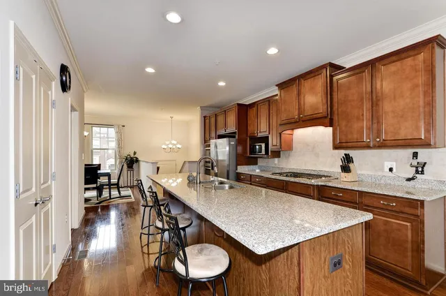 a kitchen with stainless steel appliances granite countertop a sink a stove a refrigerator cabinets and living room view