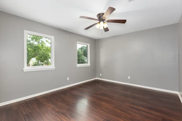 an empty room with wooden floor and windows