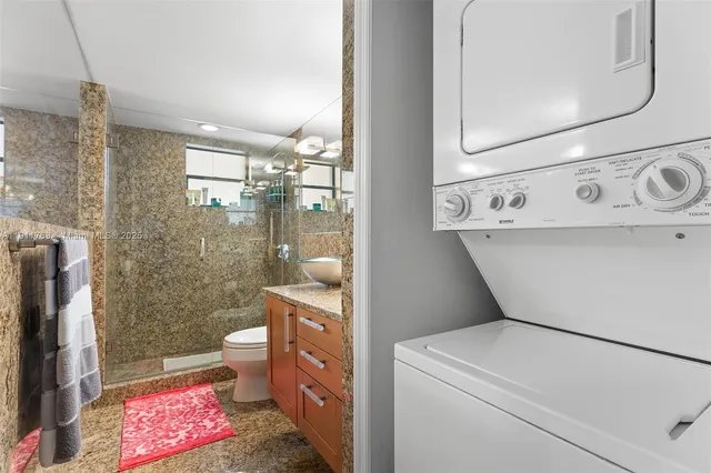 a bathroom with a granite countertop sink a toilet a mirror and shower