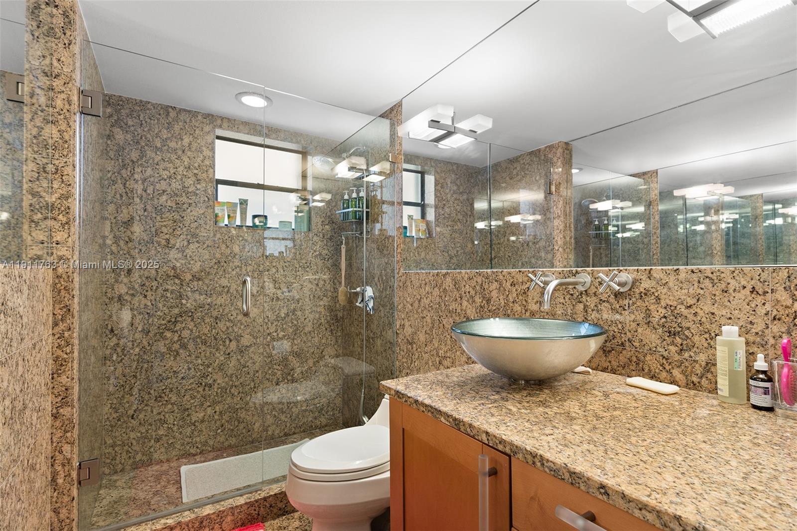 1775 Washington Avenue, Unit 14F Miami Beach, FL 33139 - Photo 21 of 25 a bathroom with a granite countertop sink a toilet a mirror and shower