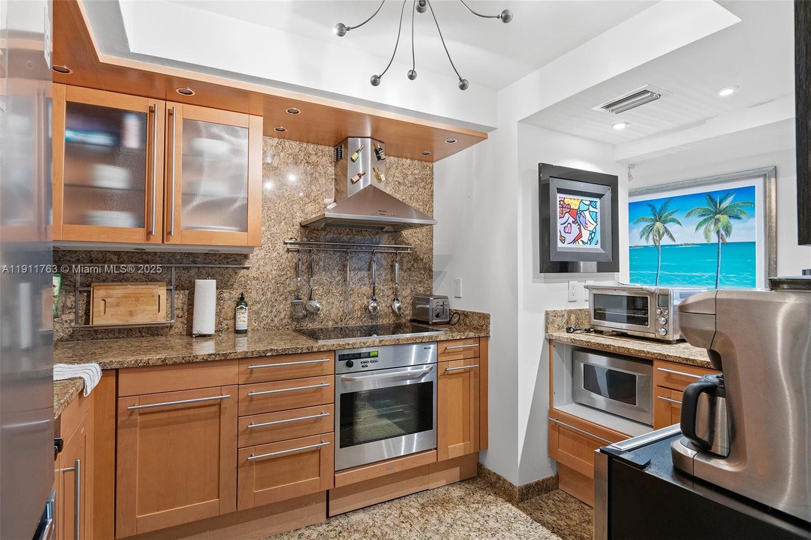 1775 Washington Avenue, Unit 14F Miami Beach, FL 33139 - Photo 7 of 25 a kitchen with stainless steel appliances granite countertop a stove and a refrigerator