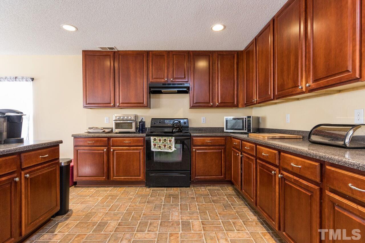 6122 Ricker Road Raleigh, NC 27610 - Photo 9 of 20 a kitchen with stainless steel appliances granite countertop wooden cabinets a stove top oven a sink and dishwasher