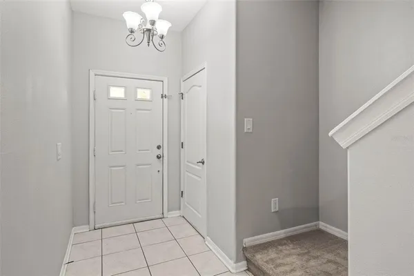 a view of an empty room with chandelier fan and entryway