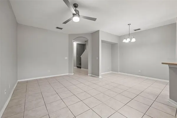 a view of an empty room with a chandelier fan