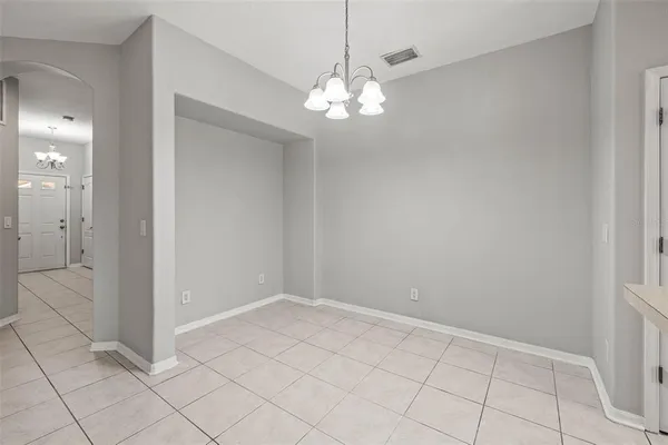 a view of an empty room with chandelier fan