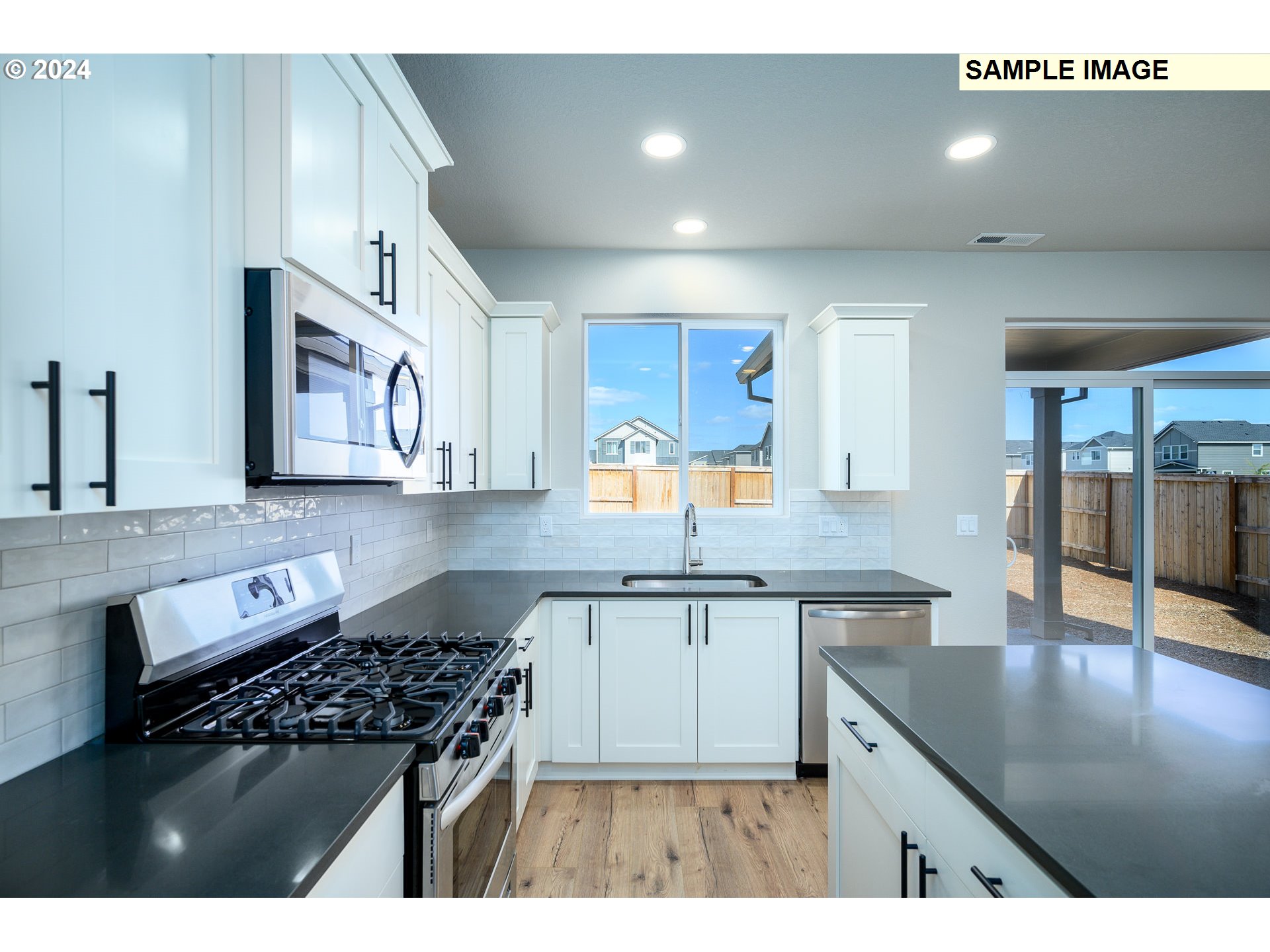 10572 Southeast Heritage Road, Unit 308 Happy Valley, OR 97086 - Photo 10 of 22 a kitchen with stainless steel appliances granite countertop a stove a sink dishwasher and cabinets with wooden floor