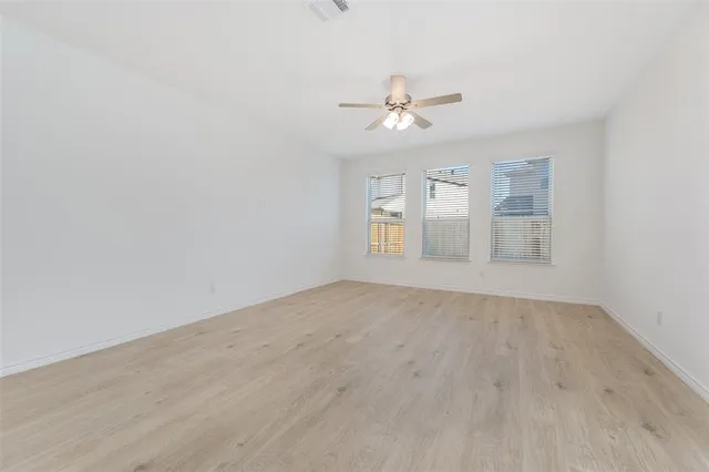 a view of empty room with wooden floor and fan
