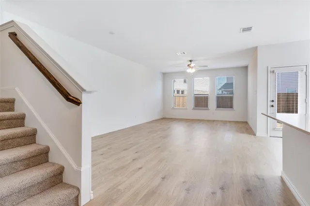 a view of an empty room with wooden floor and stairs