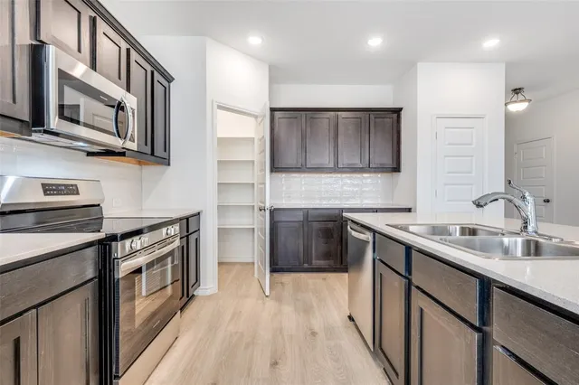 a kitchen with stainless steel appliances granite countertop a stove a sink and a microwave