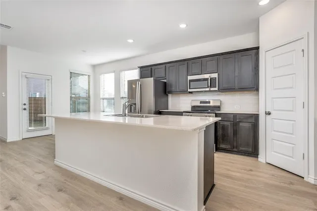 a kitchen with kitchen island granite countertop a stove a sink and a refrigerator