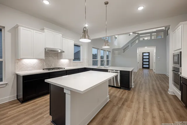 a large kitchen with stainless steel appliances a large center island attached withe living room