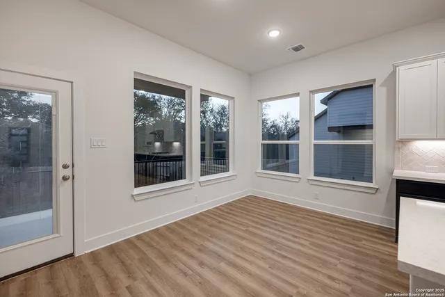 a view of an empty room with a window and wooden floor