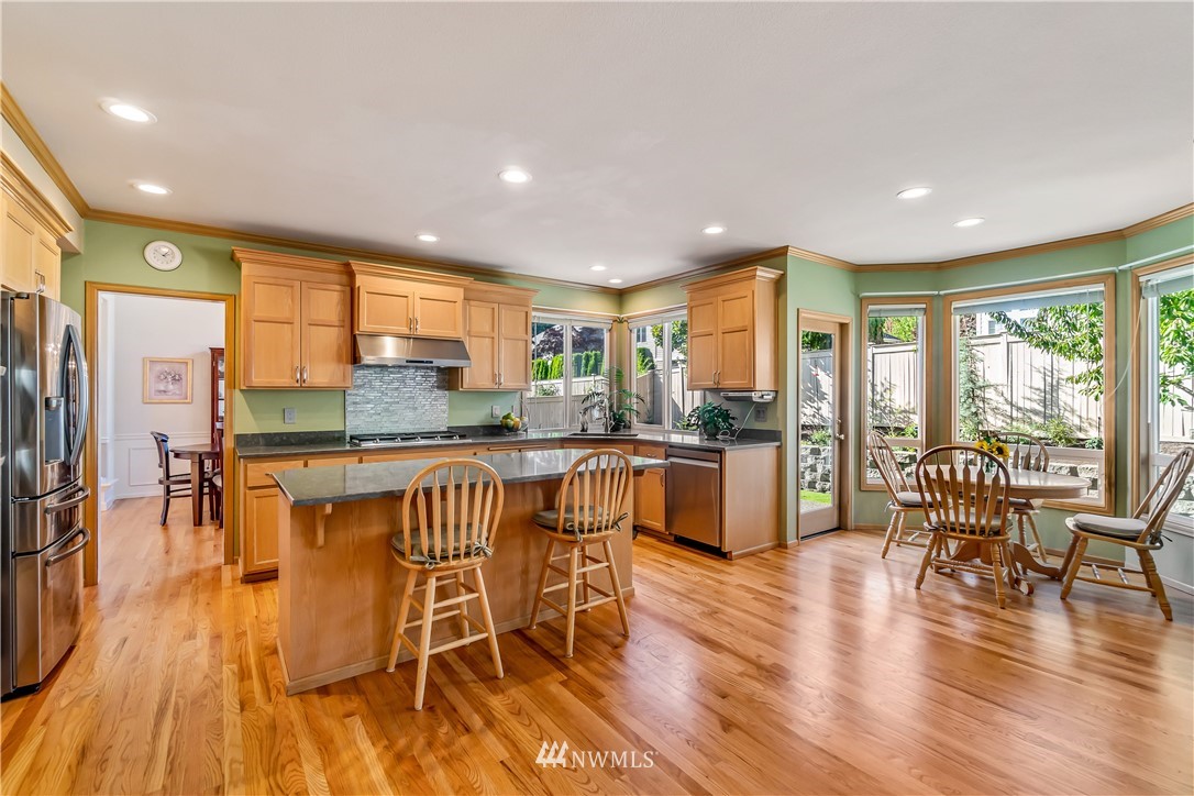 3009 214th Street Southeast Bothell, WA 98021 - Photo 11 of 36 a kitchen with stainless steel appliances granite countertop a stove top oven a dining table and chairs