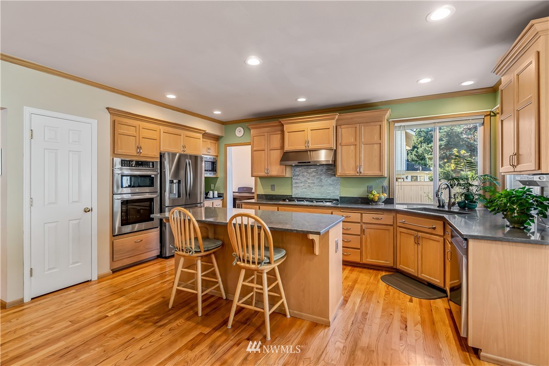 3009 214th Street Southeast Bothell, WA 98021 - Photo 12 of 36 a kitchen with stainless steel appliances granite countertop a stove and a wooden floors