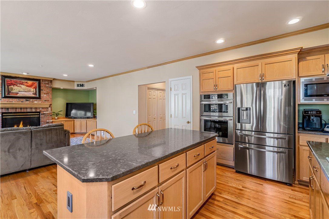 3009 214th Street Southeast Bothell, WA 98021 - Photo 14 of 36 a kitchen with stainless steel appliances granite countertop a refrigerator a stove and a sink with wooden floor