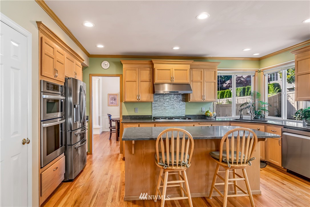 3009 214th Street Southeast Bothell, WA 98021 - Photo 16 of 36 a kitchen with stainless steel appliances granite countertop a stove top oven a dining table and chairs
