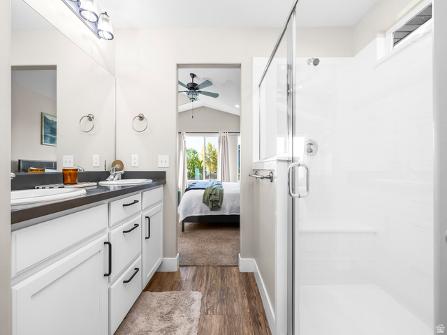 7 Sterling Loop Vineyard, UT 84059 - Photo 22 of 43 Dual vanity with dark countertops and white cabinetry, a glass-enclosed shower with white tiled walls, and wood-finish flooring