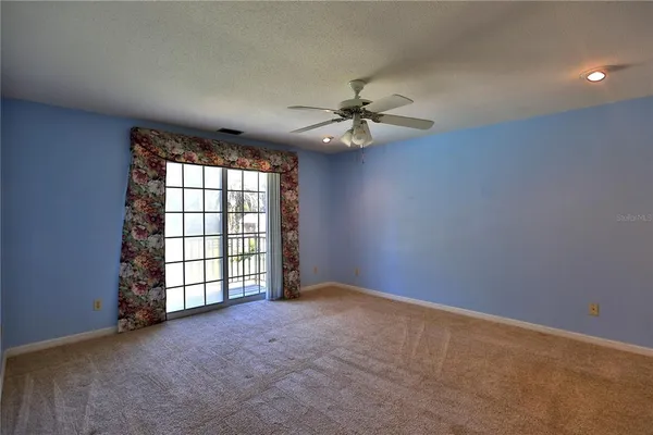 an empty room with windows and ceiling fan