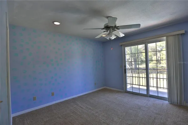 an empty room with a ceiling fan and windows