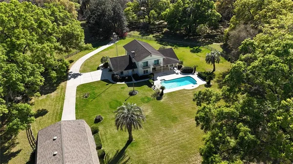 an aerial view of a house with swimming pool and large trees