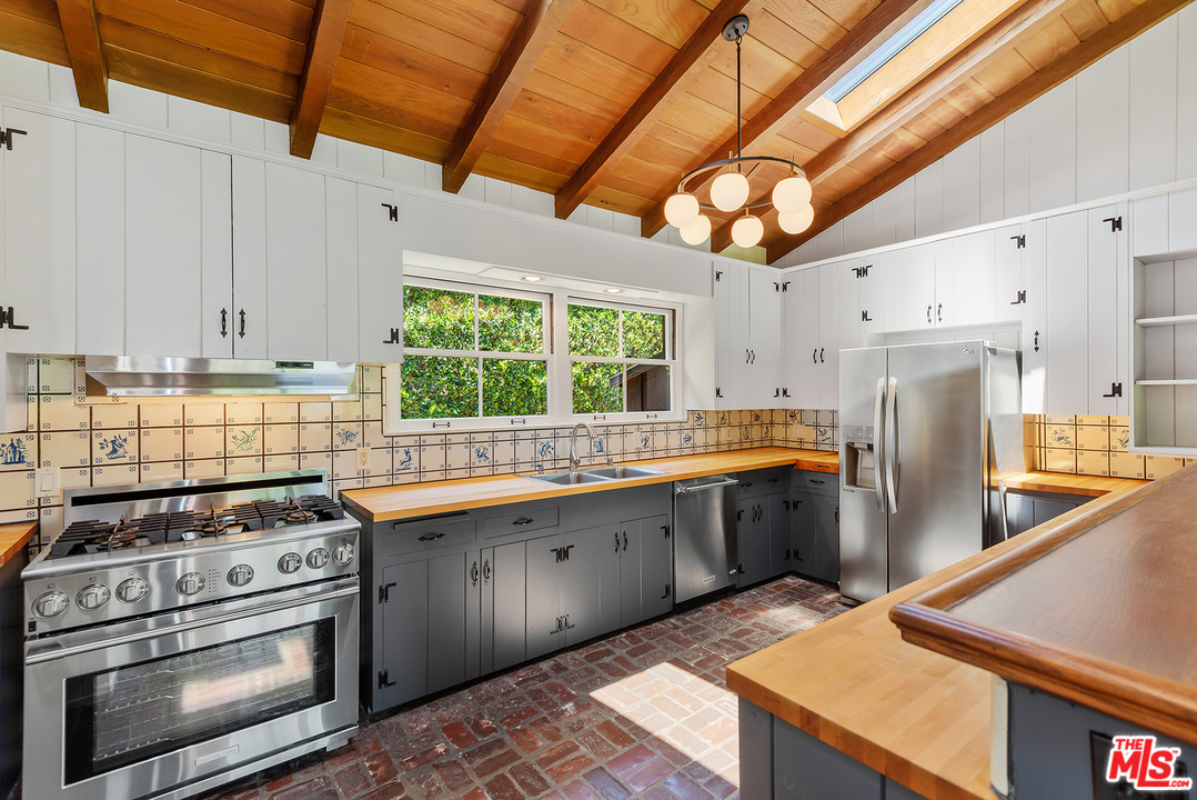 13238 Riviera Ranch Road Los Angeles, CA 90049 - Photo 11 of 28 a kitchen with stainless steel appliances granite countertop a sink a stove and a refrigerator