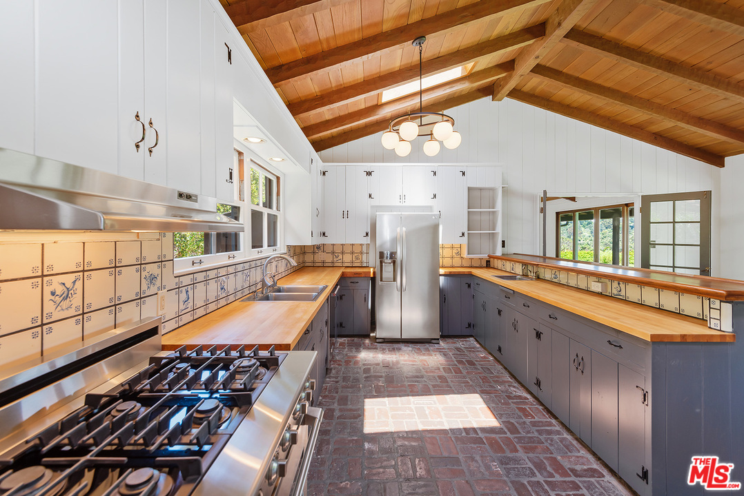 13238 Riviera Ranch Road Los Angeles, CA 90049 - Photo 12 of 28 a kitchen with stainless steel appliances granite countertop a sink and wooden cabinets